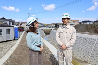 前代川の整備について職員がリポーターに説明する様子